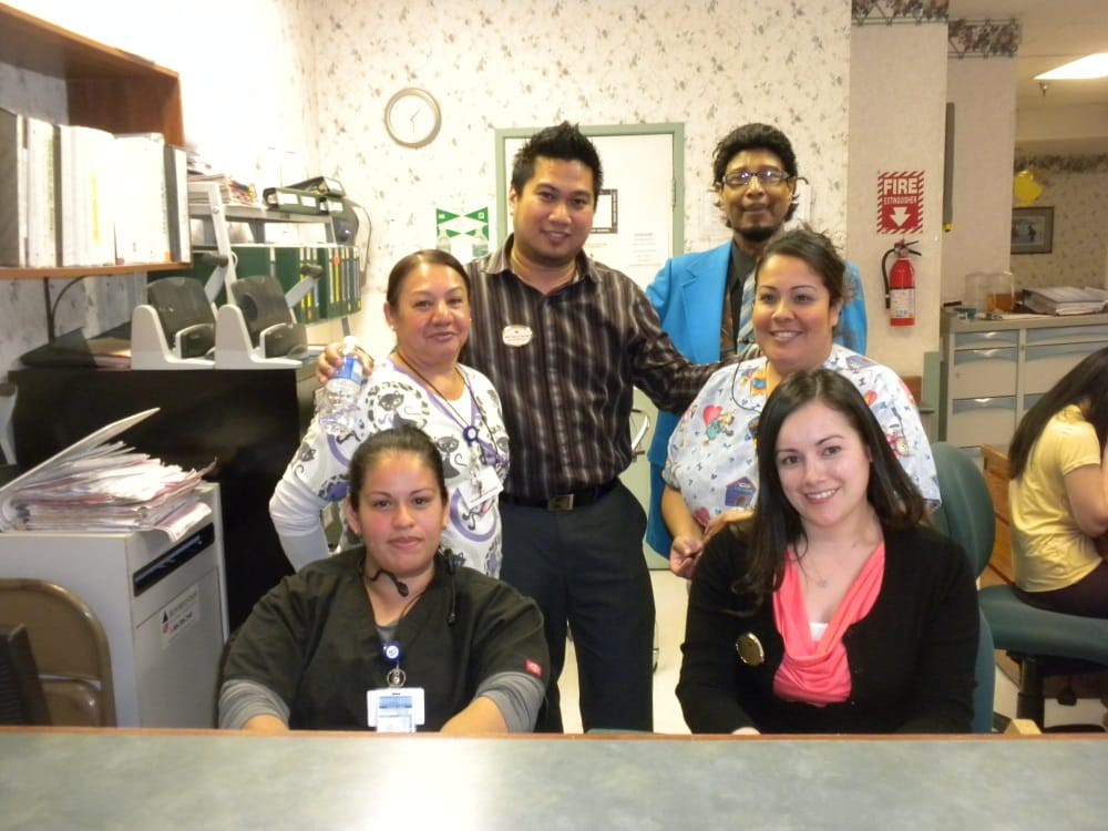 A group of colleagues gathered together in an office setting, smiling at the camera.