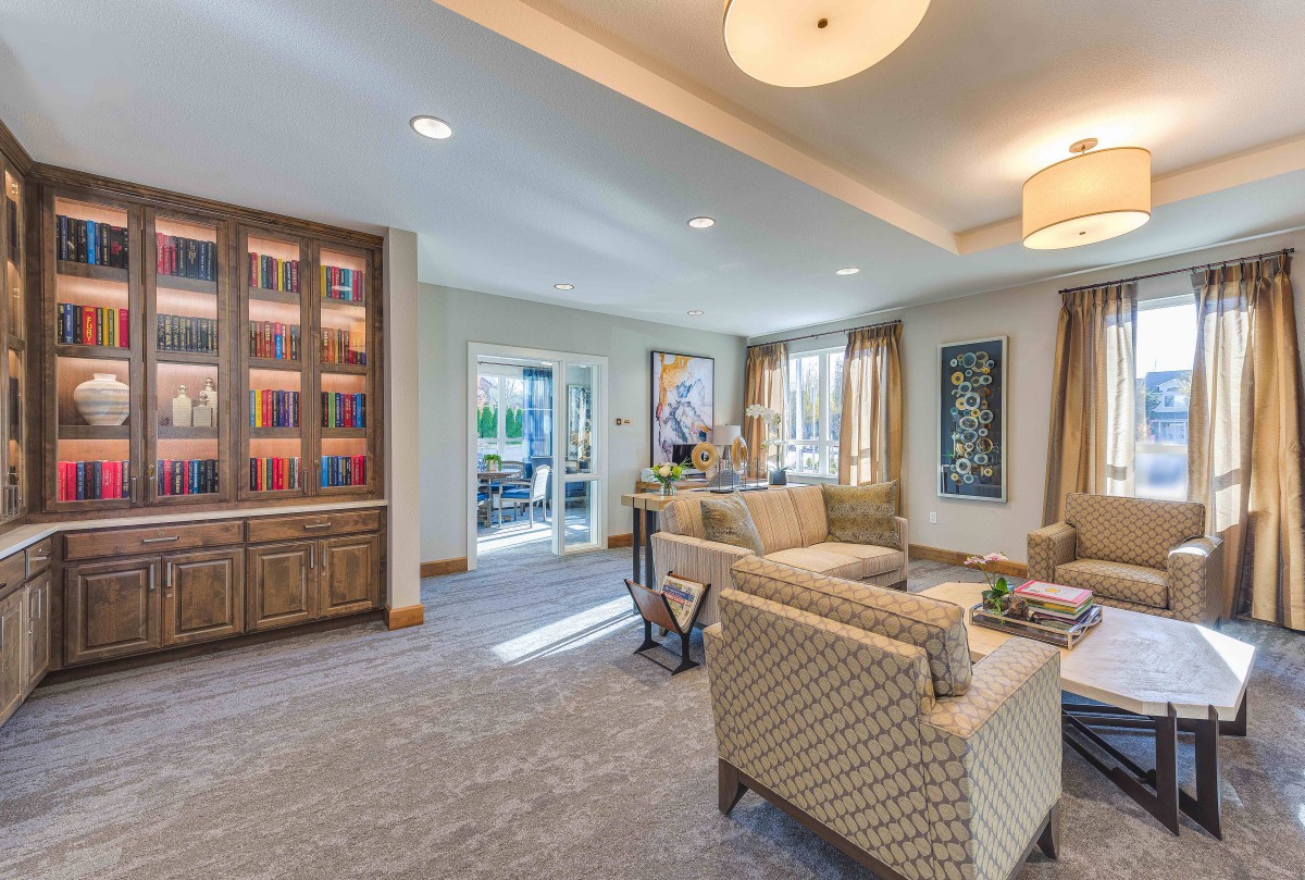 A cozy and well-lit living room with comfortable seating and a bookshelf.