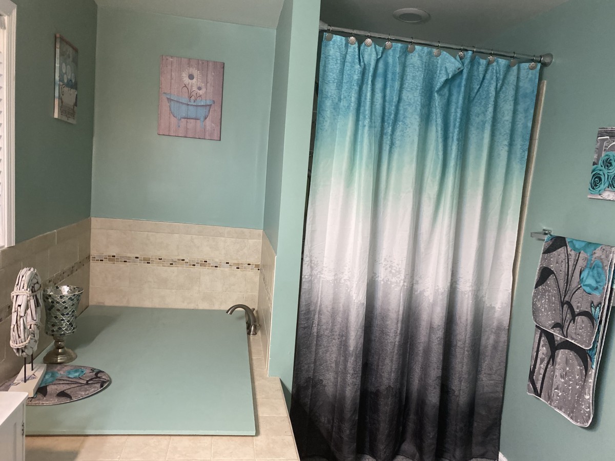 A bathroom with a gradient shower curtain and wall art.