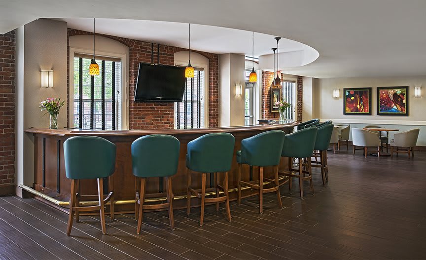 A modern bar interior with teal stools and warm lighting.