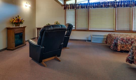 A cozy living room featuring reclining chairs and window blinds.