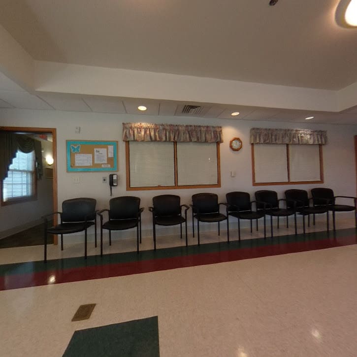 An empty waiting room with a row of chairs against the wall.