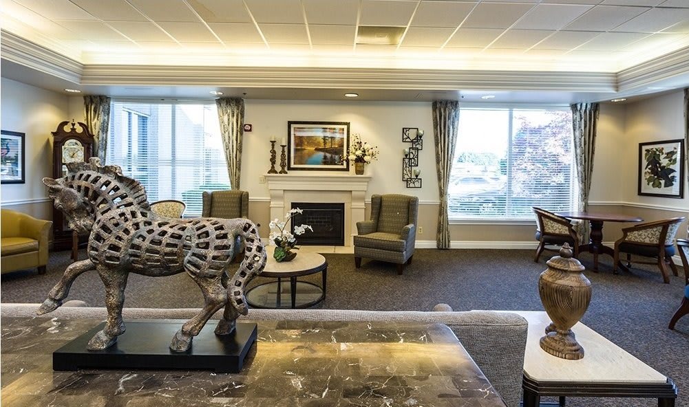 A well-decorated living room featuring a fireplace, artwork, and a horse sculpture.