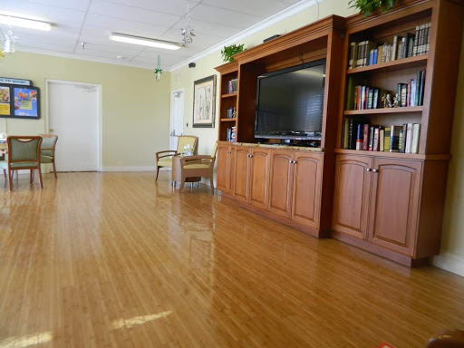 A spacious and inviting interior room featuring a wooden floor, a television set, and an organized bookshelf.