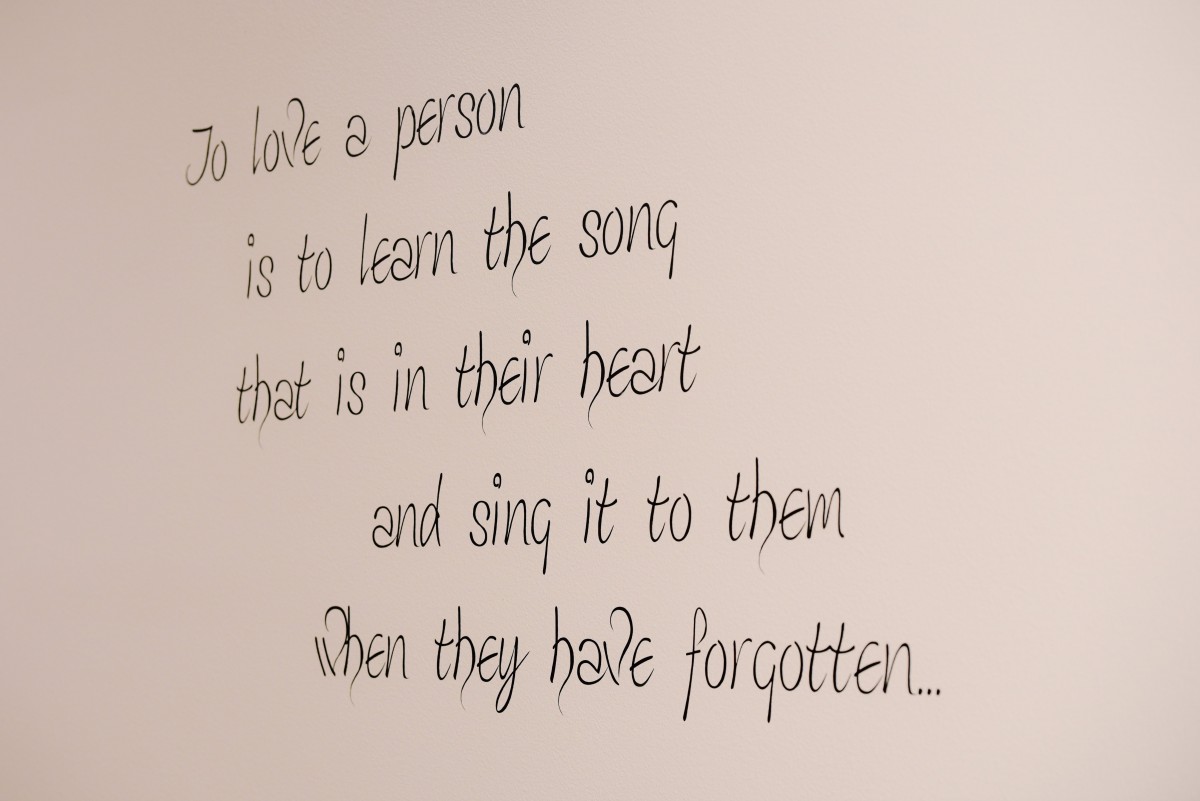 Inspirational quote about love and remembrance on a wall.