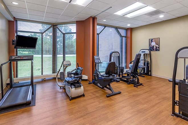 A modern fitness center with various exercise equipment and large windows.