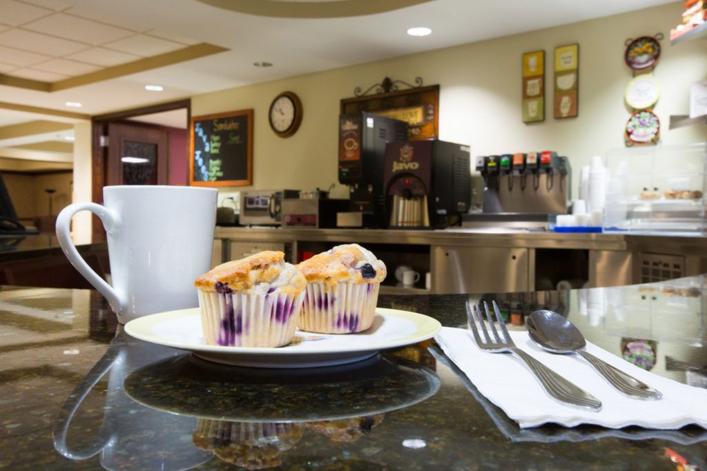 A cozy cafeteria table with blueberry muffins and a coffee cup ready for breakfast.