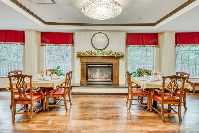 An elegant dining room featuring a cozy fireplace, chandelier, and arranged tables and chairs.