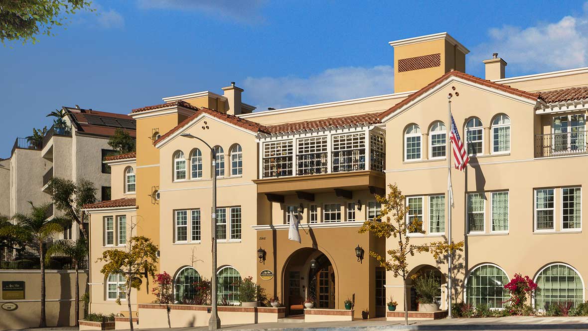 A multi-story residential building with a modern architectural design against a clear blue sky.