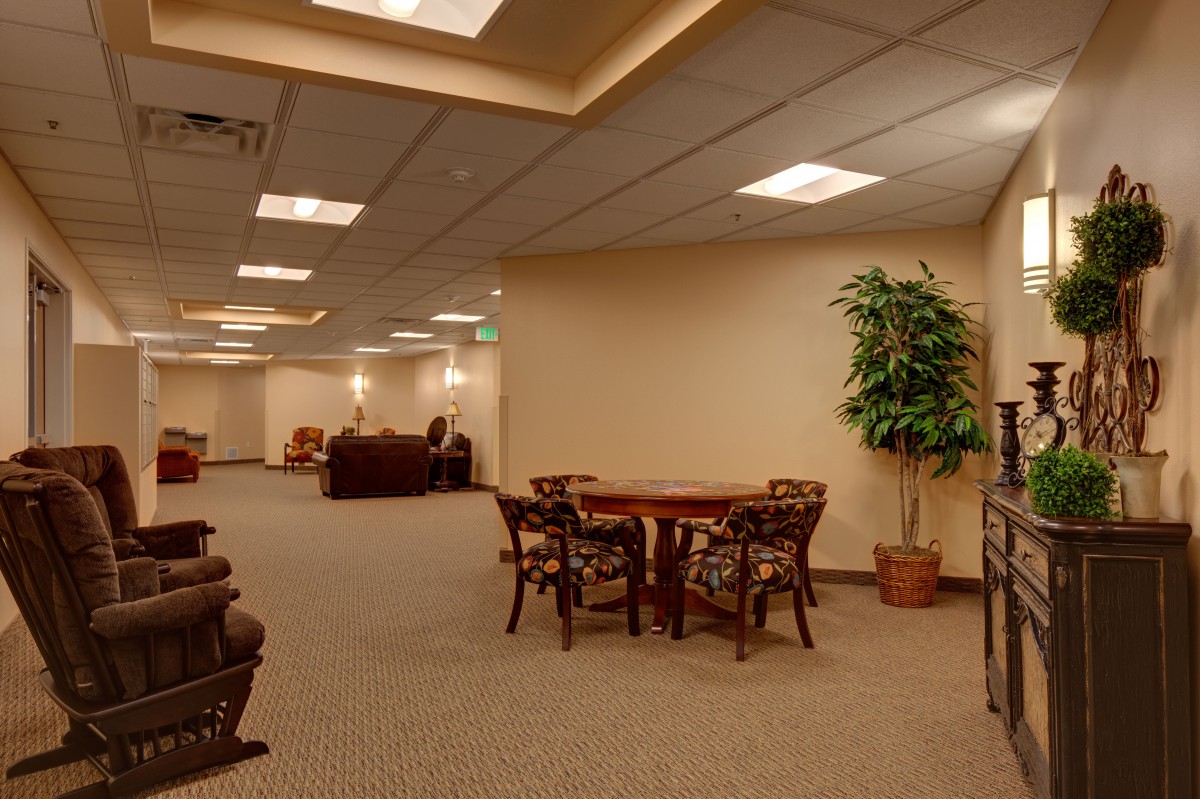 A spacious office waiting area with tables, chairs, and a potted plant.