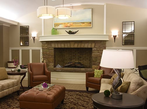 A stylish and cozy living room featuring a stone fireplace, leather chairs, and elegant decor.