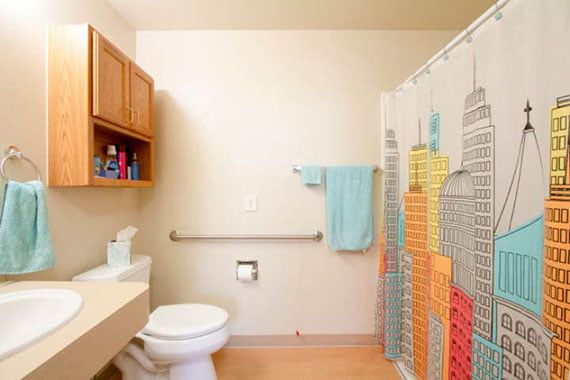 A tidy bathroom with a colorful shower curtain and light blue towel.