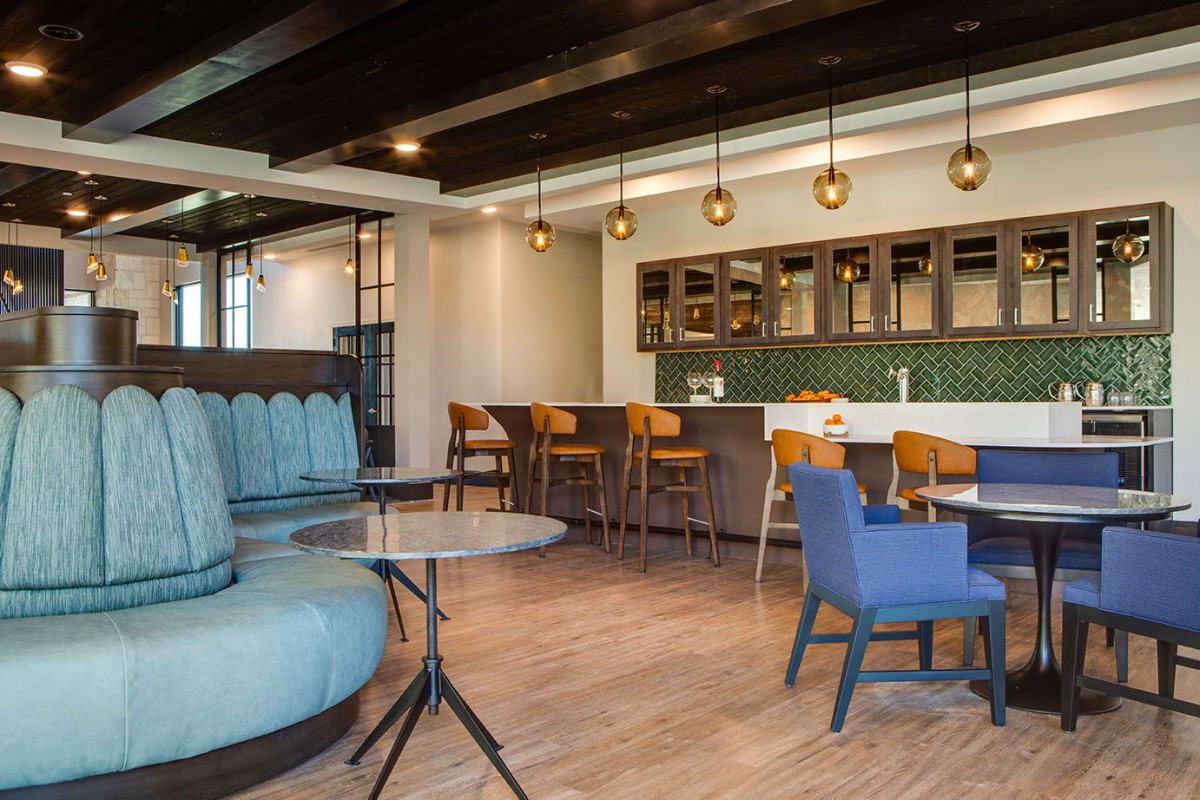A modern lounge area featuring comfortable seating, a bar with stools, and stylish lighting.