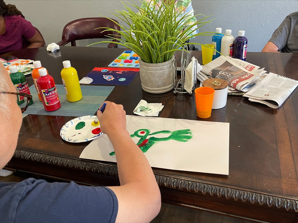 A child painting a colorful picture at a table filled with art supplies.
