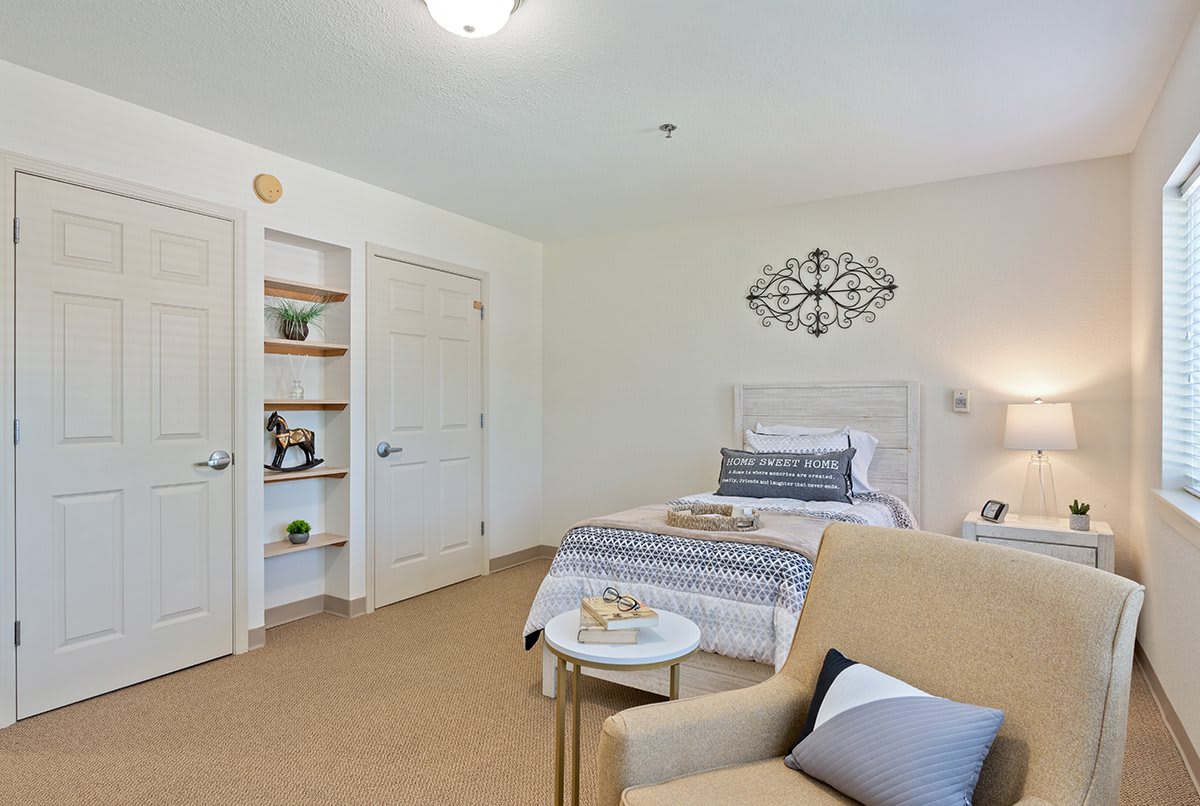 A modern, minimalist bedroom with a bed, armchair, and decorative elements.