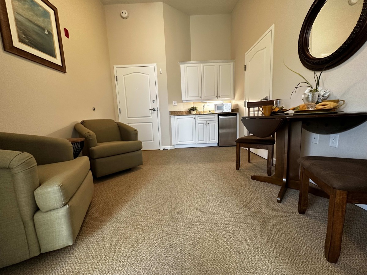 A cozy living room with seating and a kitchenette.