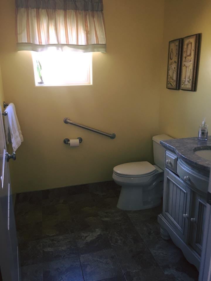A small bathroom with a toilet, sink, and handrail.
