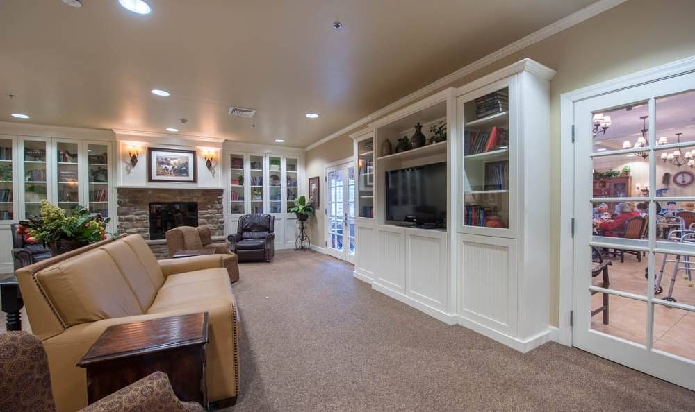A cozy living room with a fireplace, built-in bookshelves, and a large television.