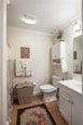 A neatly organized bathroom featuring a sink, toilet, mirror, and decorative elements.
