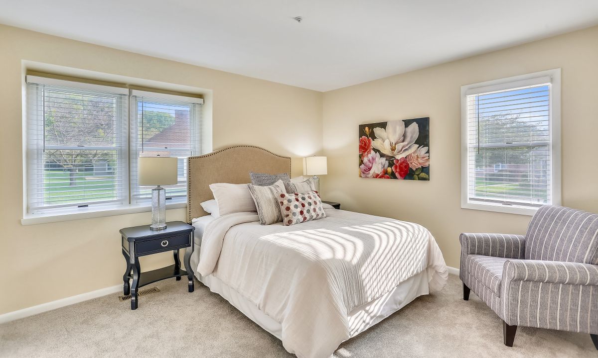 A cozy bedroom with a neatly made bed, bedside lamps, and a decorative painting on the wall.