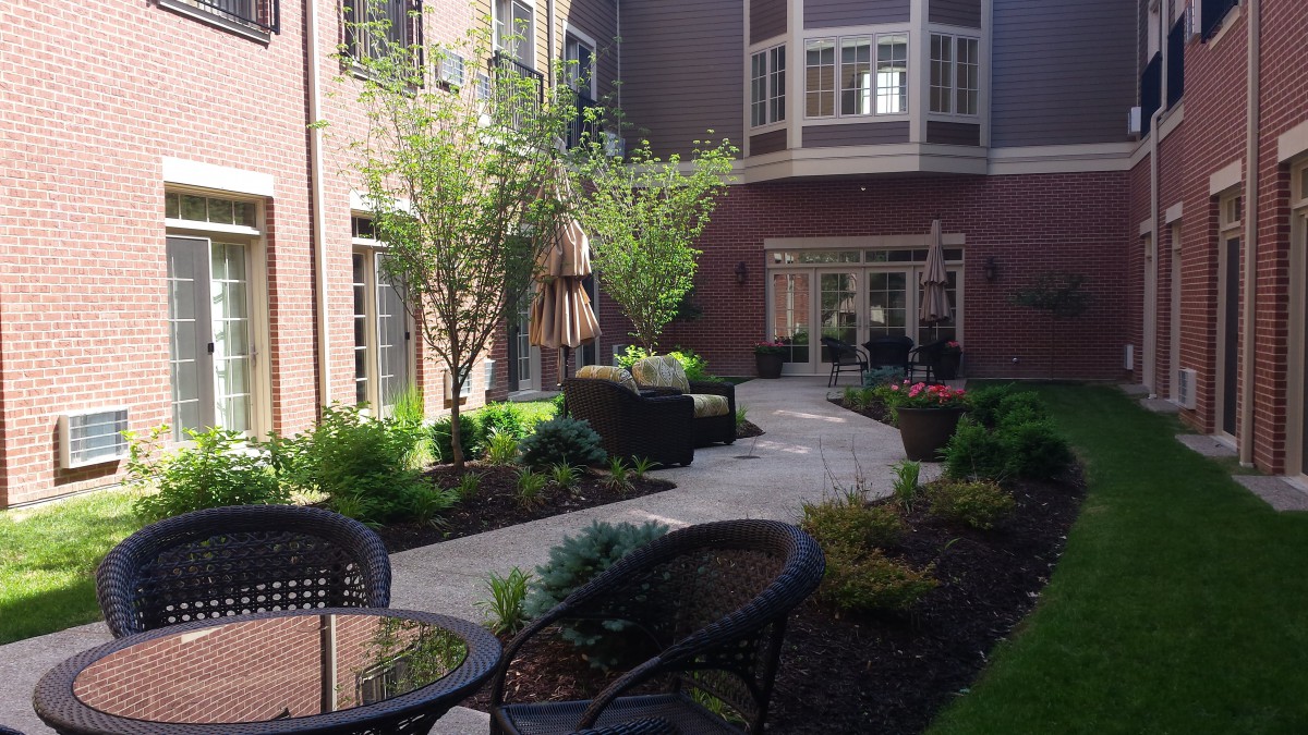 A beautifully landscaped courtyard with a walkway and patio seating.