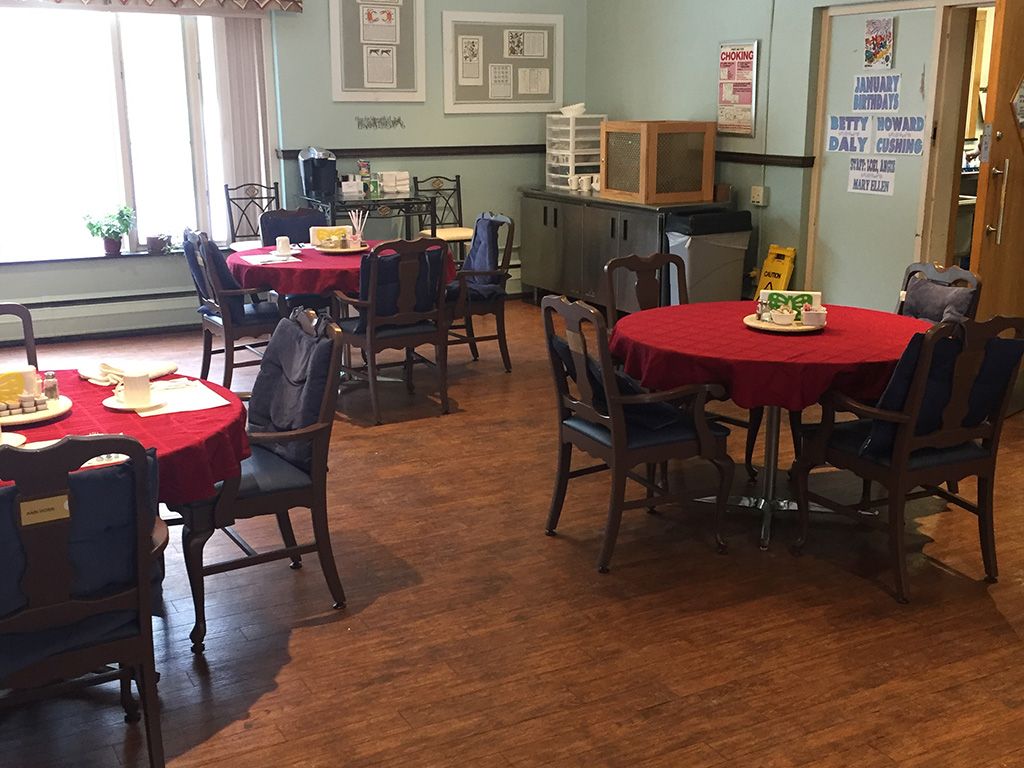 An indoor dining area with multiple tables covered in red tablecloths and surrounded by chairs.