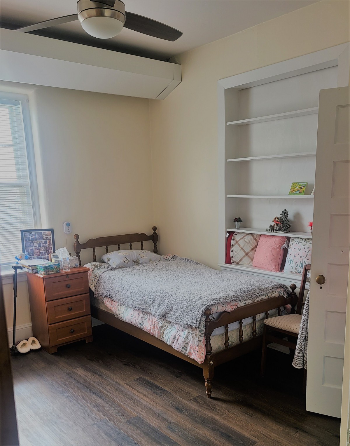 A cozy bedroom with a single bed, bookshelf, and wooden flooring.