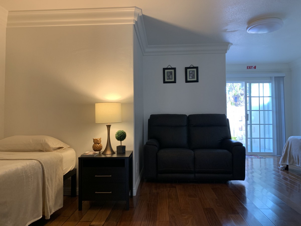A cozy living space featuring a sofa, a lamp on a side table, and hardwood flooring.