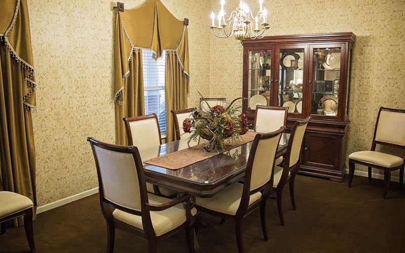 A traditional dining room with a wooden table, upholstered chairs, and a chandelier.