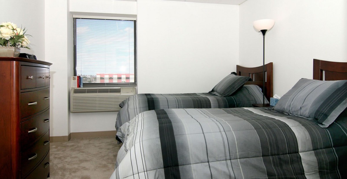 A minimalist bedroom with two twin beds and a view through the window.