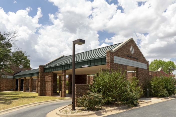 A brick building with a green roof under a cloudy sky.