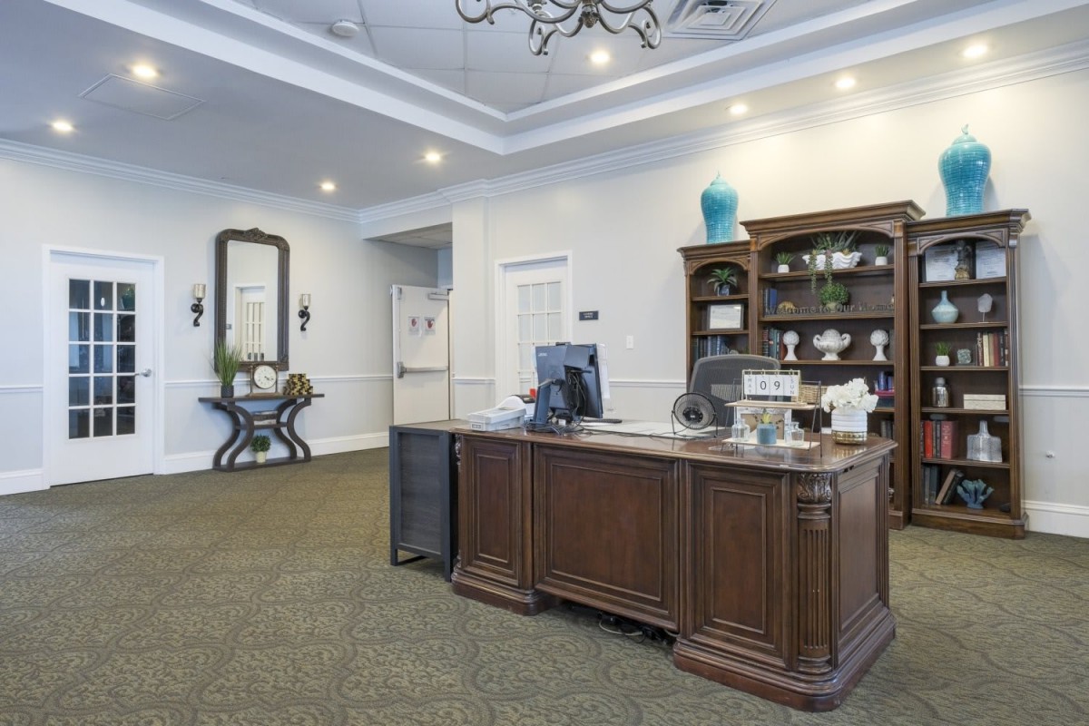 A well-decorated office reception area with a large wooden desk and elegant furnishings.