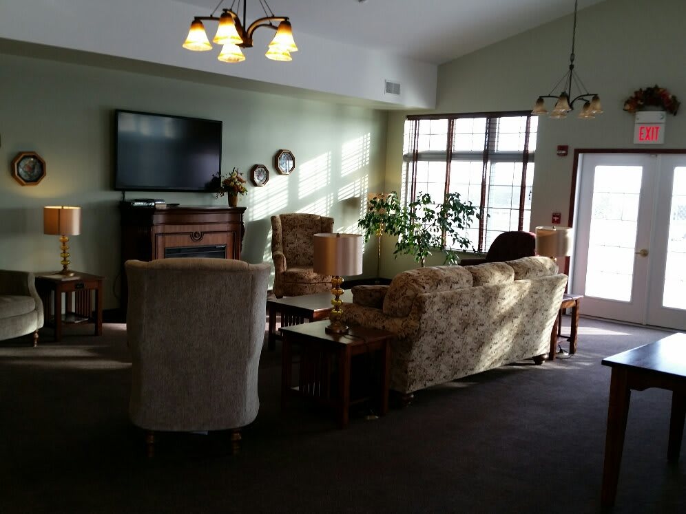 A cozy living room with comfortable seating, a television, and large windows allowing natural light.