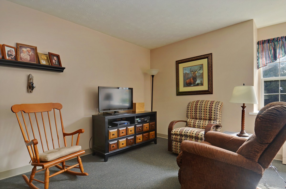 A cozy living room with a television, comfortable chairs, and a rocking chair.