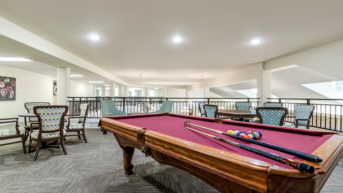 A spacious billiard room featuring a pool table and seating area.