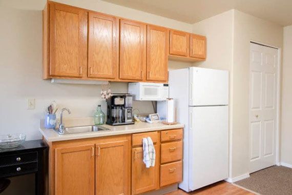 A cozy kitchen with wooden cabinets, a white refrigerator, a microwave, and a coffee maker on the countertop.