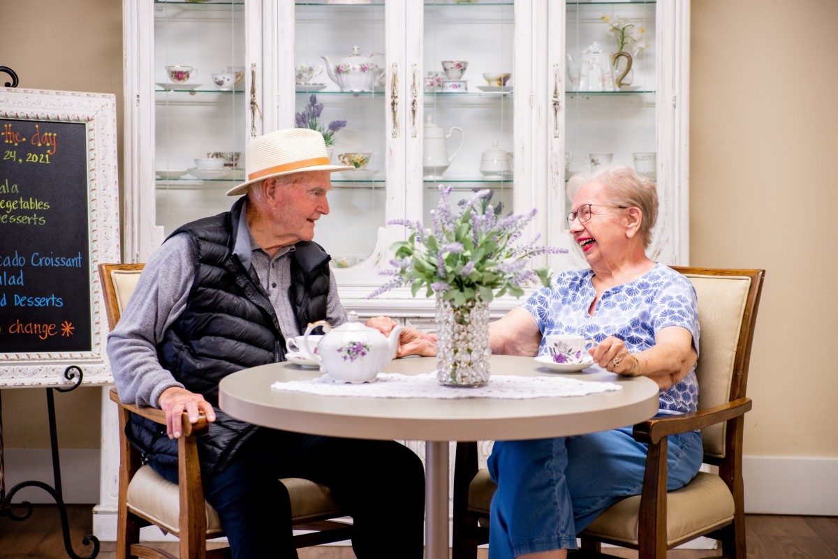 An elderly couple enjoying a cheerful conversation over tea at home.