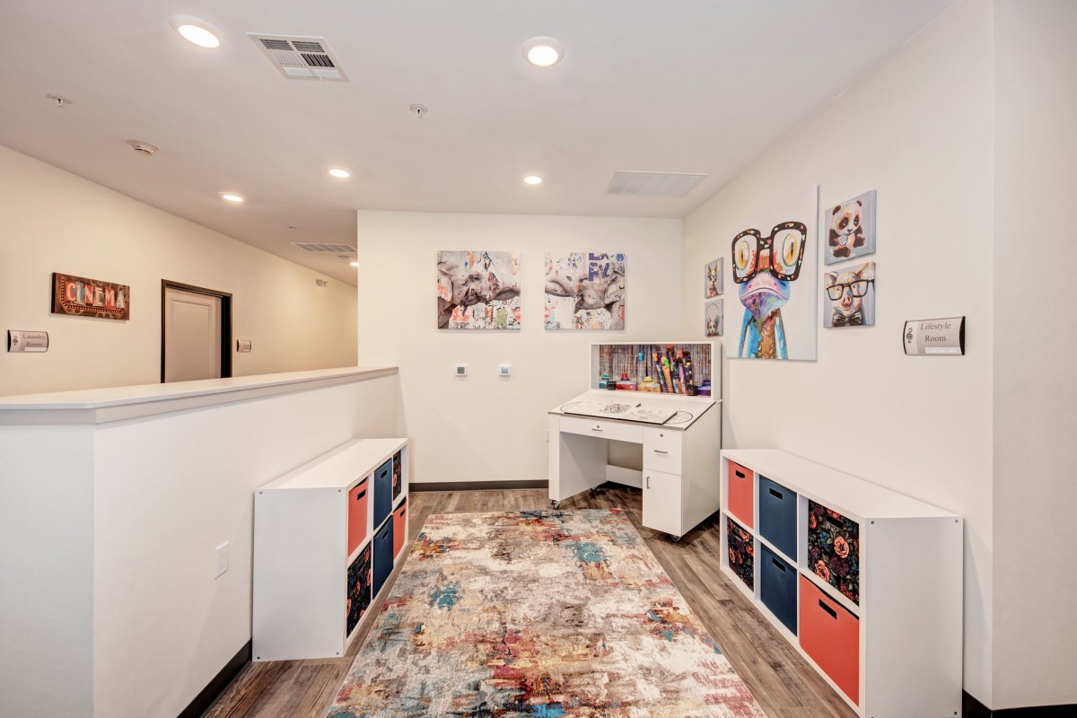 A bright and colorful playroom with children's furniture, wall art, and storage organizers.