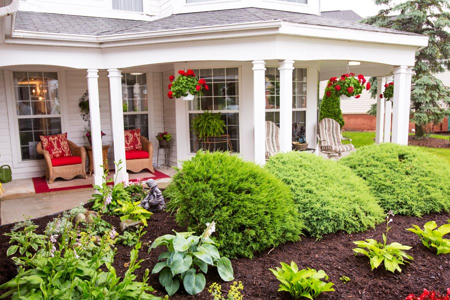 A well-maintained front porch with lush greenery and hanging flower baskets.