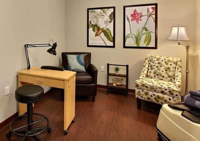 A cozy office space featuring a small desk, chairs, and framed artwork on the wall.