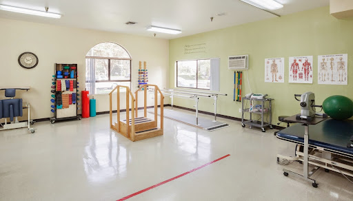 A bright and open physical therapy room equipped with exercise tools.