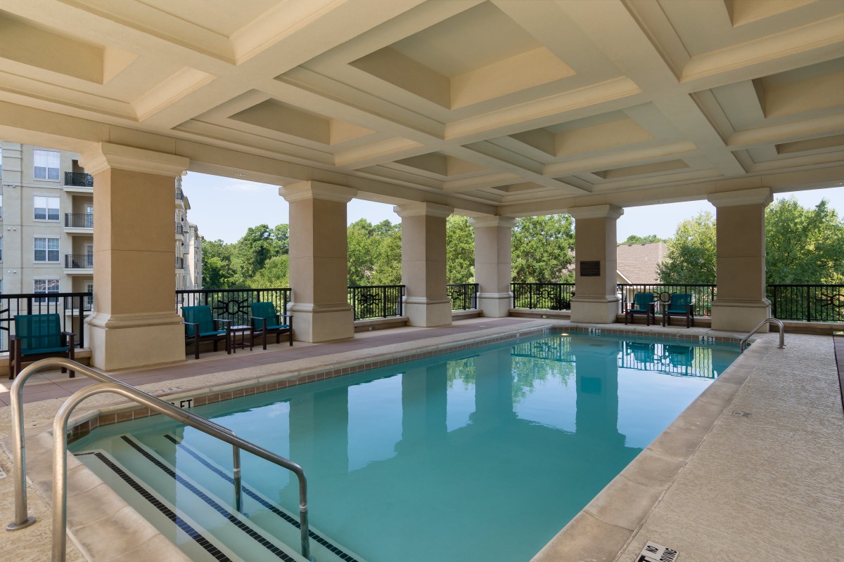 A luxurious indoor swimming pool with elegant columns and scenic outdoor views.
