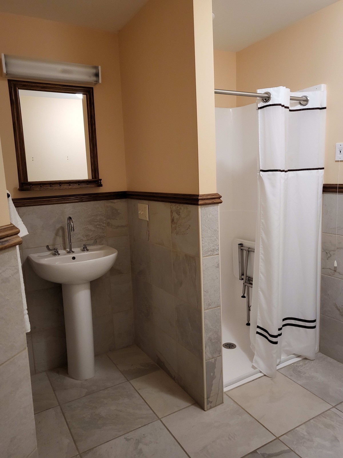 A bathroom featuring a pedestal sink and a shower with a curtain.