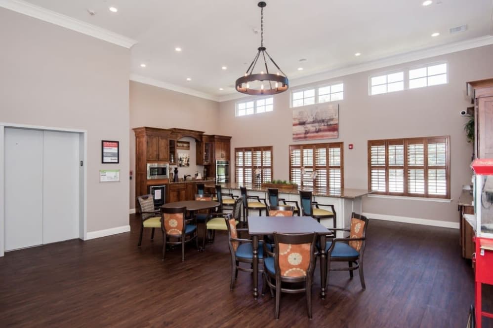A spacious dining area with modern furniture, wooden floors, and a kitchenette.