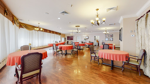 An inviting dining area featuring well-arranged tables with red tablecloths, surrounded by comfortable chairs and warm lighting.