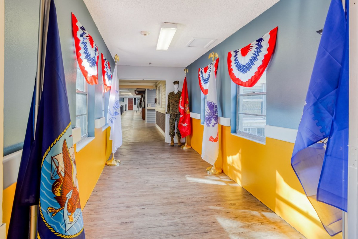 A hallway adorned with patriotic red, white, and blue bunting and various military flags.