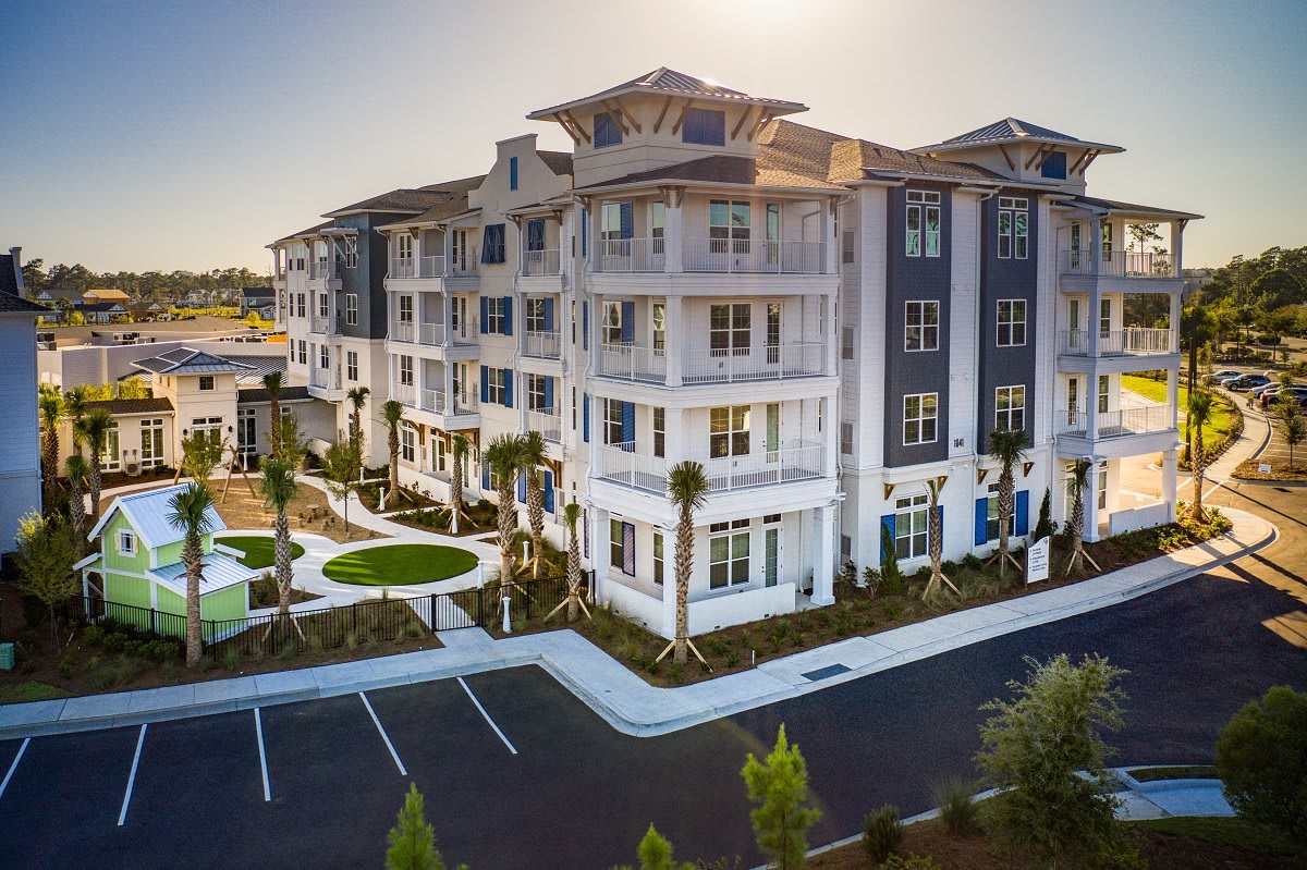A modern apartment complex with landscaped surroundings and a parking lot.