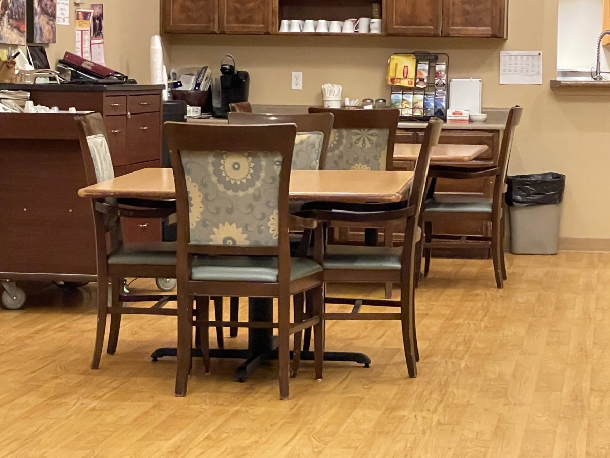 A kitchenette with a dining table and chairs alongside a coffee station.