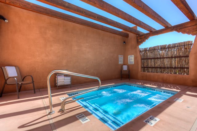 An inviting outdoor hot tub under a wooden pergola on a sunny day.
