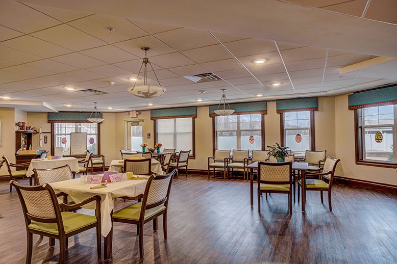 Spacious dining area with neatly arranged tables and chairs, featuring large windows and warm lighting.